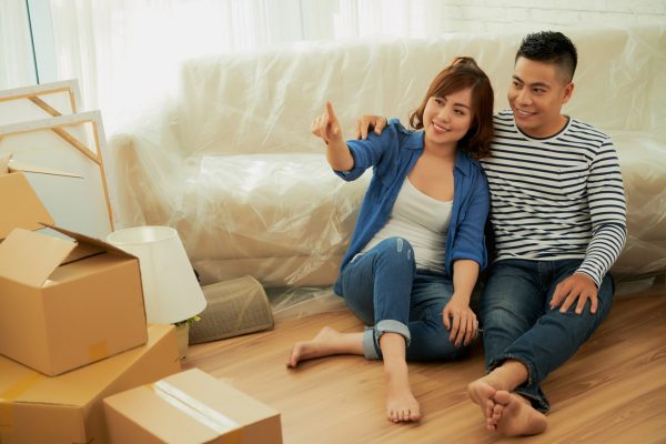 Smiling Asian couple discussing how they will design new apartment