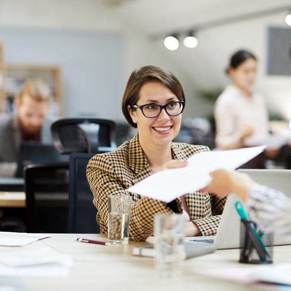 smiling-businesswoman-giving-documents-to-YLNUKBJ.jpg